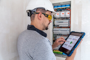 Electrical technician looking focused while working in a switchboard with fuses.