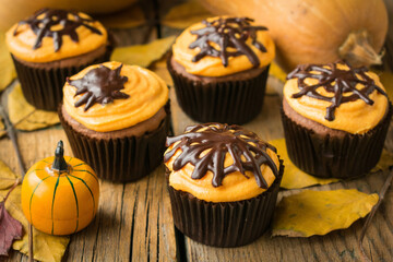 Pumpkin muffins with chocolate decor and cream of cottage cheese on Halloween. Style vintage. Selective focus
