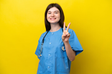 Young surgeon doctor Russian woman isolated on yellow background smiling and showing victory sign