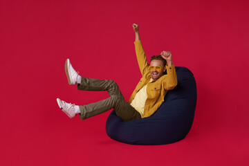 Happy handsome man sits cozy excited in victory of his sports team or business success in beanbag,...
