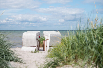 Romantic sea scene at white beach with beach chair at summer sunny day in north Germany - obrazy, fototapety, plakaty
