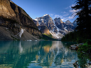 On the shore of Moraine Lake in Banff with the three sisters reflected in the calm lake waters