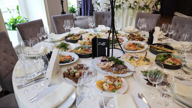 Wedding banquet in a restaurant with a lot of food. Festive served plates on the round table. A table set with dishes waiting for the start of a large banquet. Wedding. Party. Celebration.