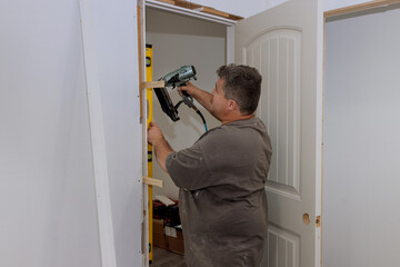 During the installation of interior doors in a new house, a trim carpenter using air nail gun