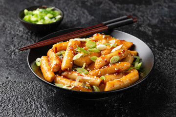 Tteokbokki, Topokki fried rice cake stick in black bowl. Korean street food