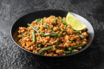 Pork Stir Fry with Green Beans, garlic, chili and ginger in black bowl. Asian food.
