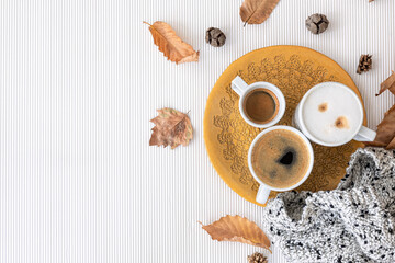 Autumn composition with cups of coffee and leaves on a white background.