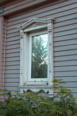 Window with decorative elements in a wooden house, carved window platbands