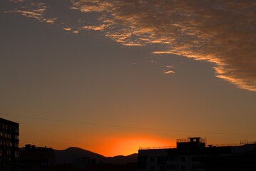 Sunrise from behind the mountains against the backdrop of urban new buildings