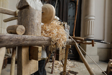Shallow depth of field (selective focus) details with a craftsman using an ancient Roman woodturning lathe to make a bowl during a historic reenactment event.