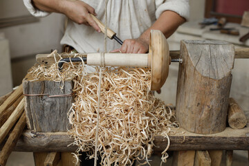 Shallow depth of field (selective focus) details with a craftsman using an ancient Roman woodturning lathe to make a bowl during a historic reenactment event.