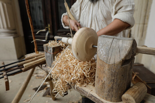Shallow depth of field (selective focus) details with a craftsman using an ancient Roman woodturning lathe to make a bowl during a historic reenactment event.
