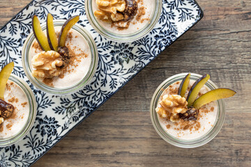 Dessert mit Pflaume, Walnuss, Frischkäse, Joghurt. Quark, Haferflocken, Marmelade und Zimt auf einem Tisch angerichtet