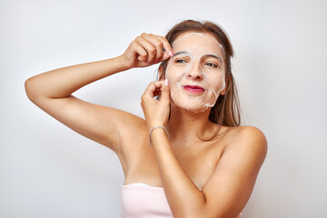 Obraz premium A girl uses a mask for facial care. Beauty concept, skin care cosmetics, facelift. Beauty salon. Removal of wrinkles.