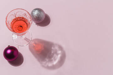Minimalistic composition of Christmas toys on a pink background with a cocktail in a glass. The concept of celebrating christmas and new year. copy space