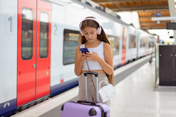 Teen girl listening to the music with headphones in a train station