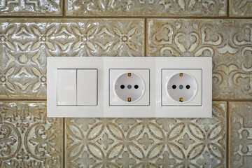 White plastic walk-through switches and sockets on a white wall.