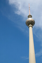The Berlin Television Tower (Fernsehturm Berlin and Berliner Fernsehturm in German), the tallest structure in Germany, with a cloudy blue sky as a backdrop on a sunny day.  Image has copy space.