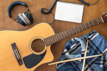 Music background with guitar, headphones and notepad, top view.