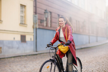 Fototapeta na wymiar smiling modern woman outdoors on city street riding bicycle