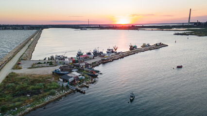 Obraz premium Aerial view of a harbor with boats sailing and docked. Photography was taken from a drone at a higher altitude in summer season at sunset.