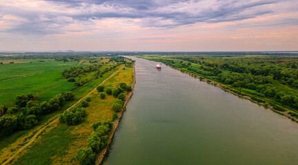 Fototapeta premium Aerial photography of a cargo transport ship seen on Danube at sunrise. Photo was taken from a drone at a higher altitude with camera lowered to keep the ship in focus.
