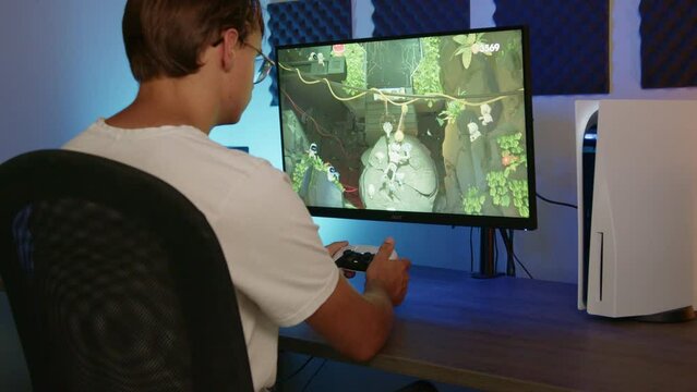 Boy Laying down his PS5 controller and walking away after gaming on his PlayStation 5 in an RGB LED room at night, Side view Wide