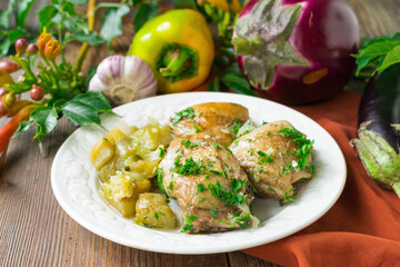 Fried chicken with eggplants on a ceramic plate. Wooden background