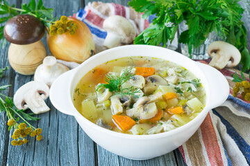 Soup with mushrooms and vegetables cooked in chicken broth. Wooden background. Selective focus