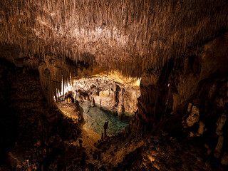 Cueva con estalactitas y estalagmitas con fondo de agua transparente 