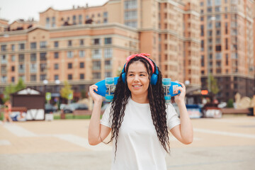 a young woman with dreadlocks holds a skateboard and listens to music.generation z