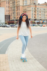 Fototapeta premium A beautiful young girl with dreadlocks rides a skateboard in sunny weather. generation z