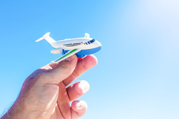 Hand holding a miniature airplane on a sunny day, summer vacation, business, travel concept.