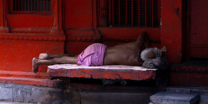 Hindu man with bare torso sleeping on a stone bench. Varanasi, Uttar Pradesh (India).