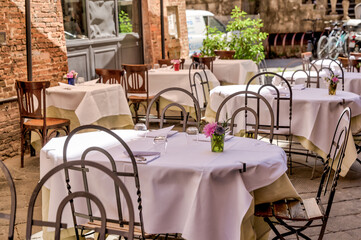 Sienna, Italy - July 14, 2022: Dining tables on a streetside patio in Siena Italy
