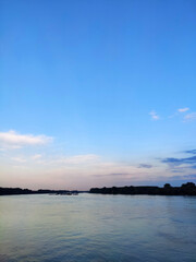 Fototapeta na wymiar Vertical image of a sunset sky with clouds and Danube river.