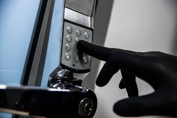 Thief in black gloves tries to enter the code into the electronic lock