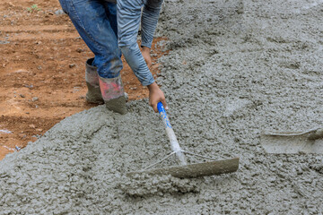 In construction site with pouring concrete for car parking driveway is the work of a worker