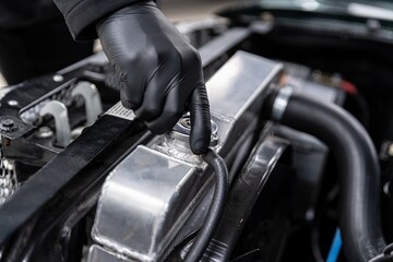 Mechanic opens the coolant filler cap in the radiator of a classic car. Car care