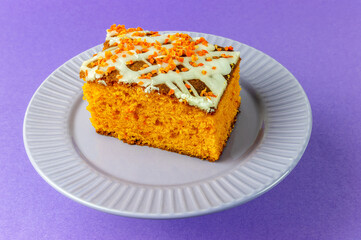slice of carrot cake with white cream on purple background