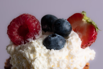 Close-up of top of appetizing muffin with delicious vegan cream and fresh berries . Place for your text. Sweet concept. Excellent image for dessert banners and advertisements. Desert background. 