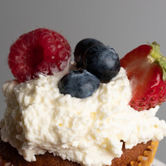 Close-up of top of appetizing muffin with delicious vegan cream and fresh berries . Place for your text. Sweet concept. Excellent image for dessert banners and advertisements. Desert background. 