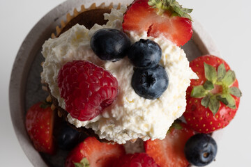 Close-up of top of appetizing muffin with delicious vegan cream and fresh berries . Place for your text. Sweet concept. Excellent image for dessert banners and advertisements. Desert background. 