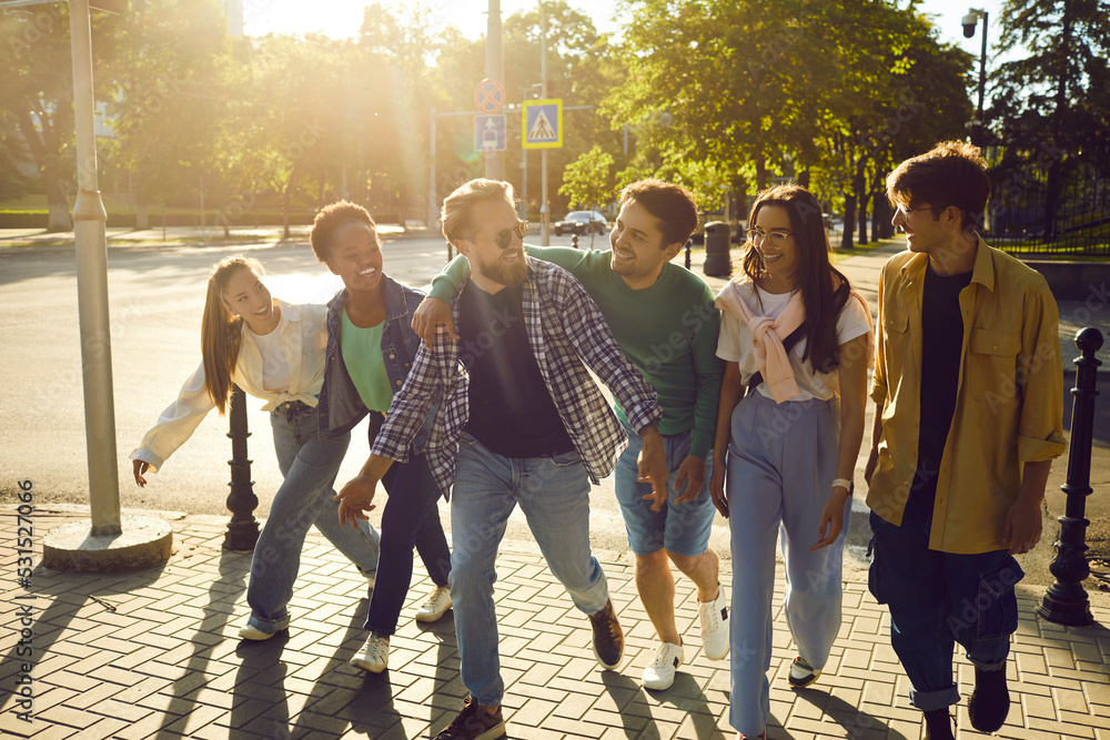 Wall mural diverse group of happy, joyful friends walking in the street. bunch of cheerful young multiethnic pe