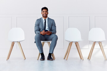 We are hiring, interview and business man worker waiting for a company management meeting. Portrait of a businessman smile from India on his phone ready for hire process in a office with motivation