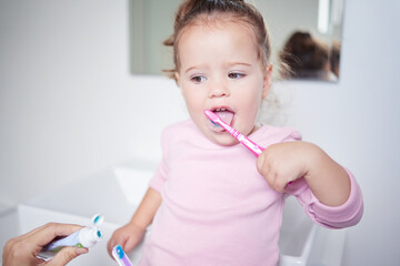 Baby learning to brush her teeth, dental and oral hygiene. Toothbrush, toothpaste and brushing...