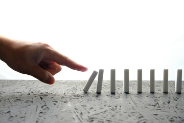 Hand pushing with a finger dominoes standing white background.