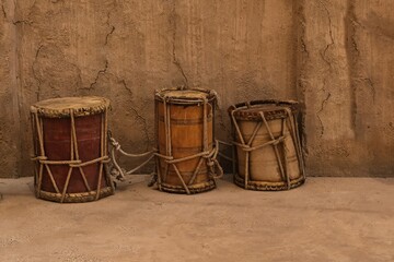 Ancient authentic folk music wooden drums in Africa and Gulf Persian Countries. Middle Eastern hand-made drums on sand wall background. 