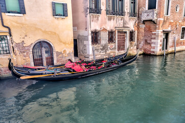Fototapeta na wymiar Venice, Italy - July 5, 2022: Building exteriors, boats and gondolas along the canals in Venice Italy 