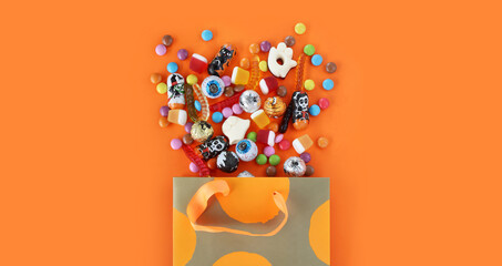 Shopping paper orange polka dot gift bag full of spilled assorted traditional Halloween candies....